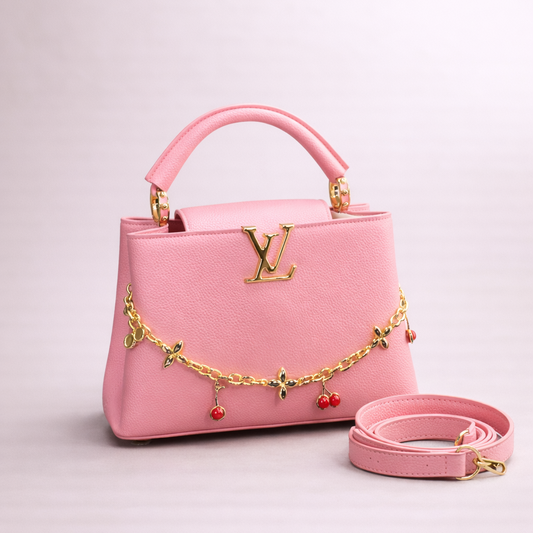 Pink handbag with gold chain and red beads on a light pink background