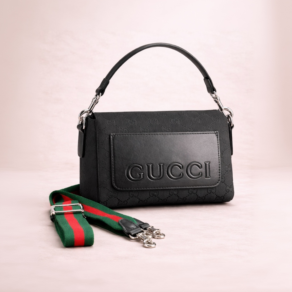 Black Gucci handbag with a green and red strap on a light pink background