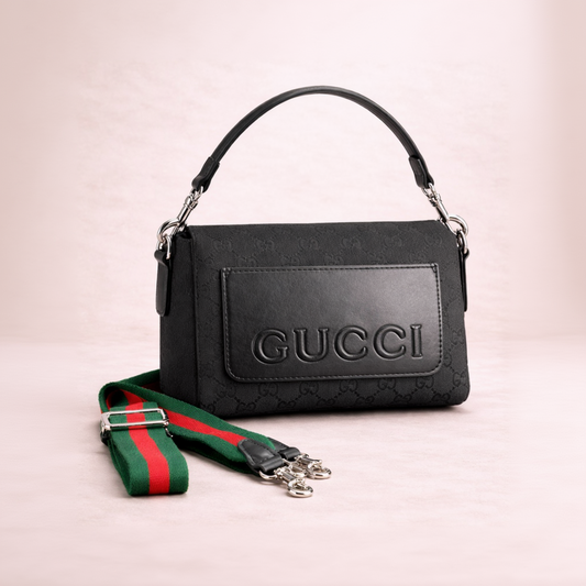 Black Gucci handbag with a green and red strap on a light pink background